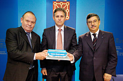 Los tres firmantes posan con una marqueta de una instalación de servicios ITV