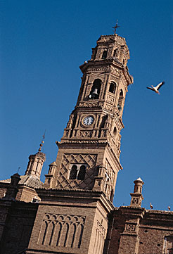 Una cigüeña volando junto a la iglesia de la Virgen del Rosario de Corella