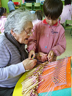 Una abuela enseña bolillos a un niño